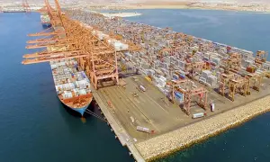 Große Containerkräne und Schiffe im Salalah Port, beladen mit unzähligen Frachtcontainern, die auf ihre Weiterreise warten.