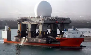 Die orangefarbene "Blue Marlin" ist ein Schwergutfrachter, der eine riesige Plattform mit einer großen weißen Kuppel transportiert.
