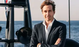 Martin Hager, mit verschränkten Armen auf einem Boot, blickt zuversichtlich in die Kamera.