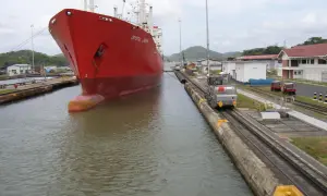 Roter Schiffsbug "Crystal Crown" in Schleuse, daneben Lokomotiven und Gebäude.