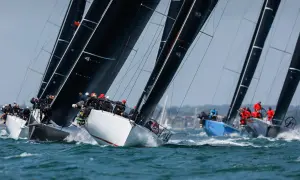 Segelboote kämpfen um die Admirals Cup. Schwarze Segel dominieren, während Teams auf dem Wasser um den Sieg ringen.