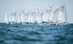 Viele Boote segeln bei der Kieler Woche. Die weißen Segel sind mit Länderkürzeln und Nummern beschriftet.