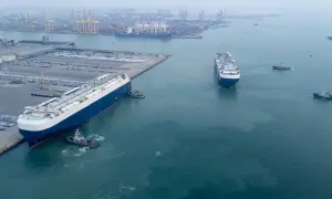 Große Autotransporter im Hafen, bereit für den Roll-on/Roll-off-Verkehr. Schlepper assistieren beim Manövrieren.