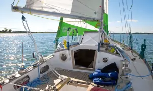 Segelboot mit grünen und weißen Segeln, die im Wind flattern. Die Website "wilfried-erdmann.de" ist auf dem Großsegel zu sehen.