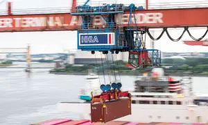 Ein großer Kran hebt einen Container im Mumbai Port. Die HHLA-Beschriftung ist auf dem Kran zu sehen.