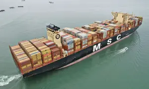Die MSC Irina, ein riesiges Containerschiff, transportiert Fracht über das Meer. Ein kleines Beiboot fährt nebenher.