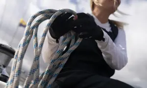 Seglerin mit Handschuhen hält Tauwerk, das für die wichtigsten Knoten auf einem Boot unerlässlich ist.