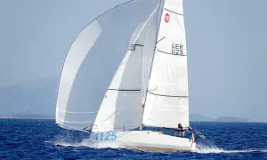 Segelboot mit zwei Personen an Bord, das auf dem Meer fährt. Die Segel sind weiß und mit der Nummer 1125 beschriftet. Dies ist ein Bild von einem Mini Transat Rennen.