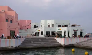 Bunte Gebäude am doha port, mit Menschen, die auf den Stufen sitzen und spazieren gehen.