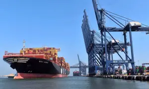 Ein riesiges Containerschiff liegt im Karachi Port vor Anker, während massive Kräne Container verladen.