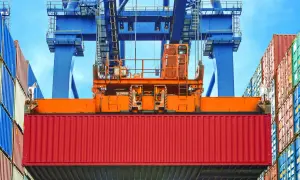 Ein roter Container wird von einem Kran gehoben. Die vgm methode 2 ist hier im Einsatz, um das Gewicht zu ermitteln.
