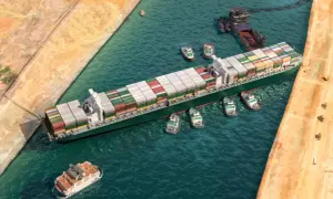 Ein Containerschiff wird von mehreren Schleppern durch einen Kanal manövriert. Der allgemeine Durchschnitt der Frachtschifffahrt.