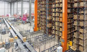Ein Hochregallager mit automatisierten Förderbändern und einem Regalbediengerät, das für **integrated logistics** optimiert ist.
