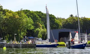 Segelboote am Steg der hanseatischen Yachtschule. Junge Segler üben auf dem Wasser.