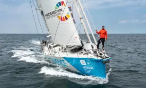 Mann auf Segelboot der Malizia Ocean Race mit Botschaft "A race we must win - Climate Action Now!".