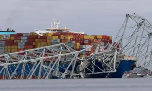 Ein Frachtschiff kollidiert mit einer Brücke, die in sich zusammenfällt. Container sind gestapelt, ein Zeichen für die globale Logistik, die in den US Ports stattfindet.