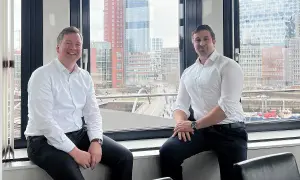 Zwei Männer, ein maritimer Anwalt und sein Kollege, sitzen vor einem Fenster mit Blick auf die Hamburger Hafencity.