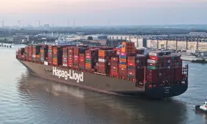 Ein riesiges Containerschiff, die "AL JMELIYAH", fährt auf einem Fluss, beladen mit bunten Frachtcontainern.