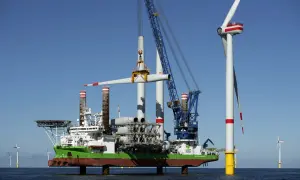 Ein Spezialschiff hebt eine Windradgondel an, um sie auf einem Turm zu montieren. Die Beine des Schiffes sind ausgefahren, um es zu jack up.