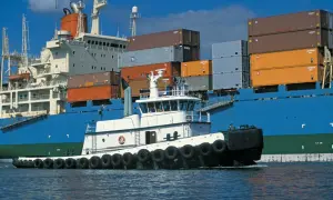 Ein kleiner Schlepper assistiert einem riesigen Containerschiff. Der Unterschied zwischen vessel und ship wird hier deutlich.