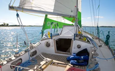 Segelboot mit grünen und weißen Segeln, die im Wind flattern. Die Website "wilfried-erdmann.de" ist auf dem Großsegel zu sehen.