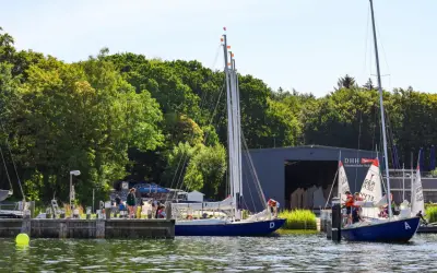 Segelboote am Steg der hanseatischen Yachtschule. Junge Segler üben auf dem Wasser.