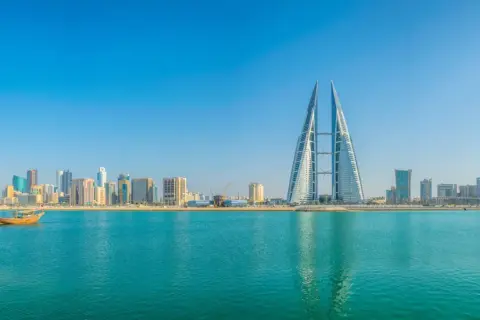 Manama Skyline mit dem Bahrain World Trade Center und traditionellen Dhaus-Booten am Khalifa Bin Salman Port.