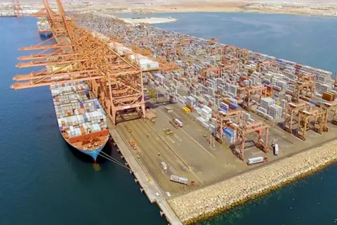 Große Containerkräne und Schiffe im Salalah Port, beladen mit unzähligen Frachtcontainern, die auf ihre Weiterreise warten.