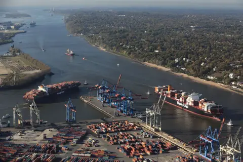 Große Containerschiffe navigieren durch die Elbe, ein Zeichen für die Bedeutung der deutschen Häfen im globalen Handel.