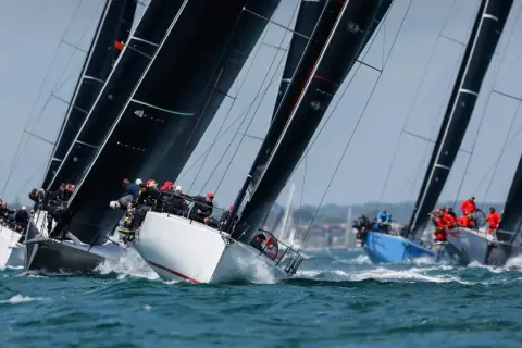Segelboote kämpfen um die Admirals Cup. Schwarze Segel dominieren, während Teams auf dem Wasser um den Sieg ringen.