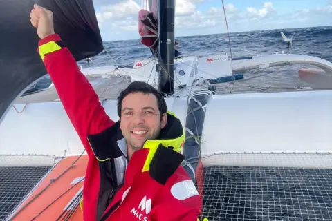 Guirec Soudée jubelt auf seinem Katamaran auf hoher See.