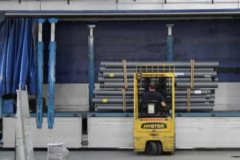 Gabelstapler lädt Rohre in einen LKW. Die Ware wird für den Versand vorbereitet, um die notify party zu informieren.