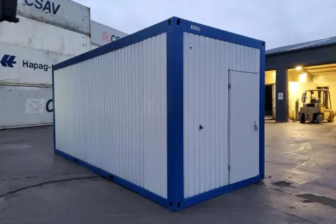 Ein blauer und weißer Container steht auf einem Container-Depot. Im Hintergrund sind weitere Container und ein Gabelstapler zu sehen.