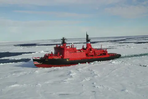 Ein rotes Eisbrecher-Schiff mit Haifischzähnen am Bug kämpft sich durch gefrorenes Wasser.