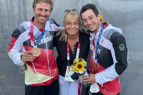 Tatjana Pokorny mit zwei Medaillengewinnern des Team Deutschland bei den Olympischen Spielen in Tokio.