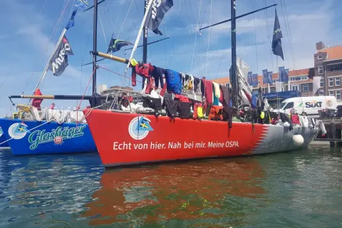 Segelboote im Hafen, Wäsche trocknet an Bord. Michael Illbrucks Boot "Meine OSPA" mit rotem Rumpf und Schriftzug.