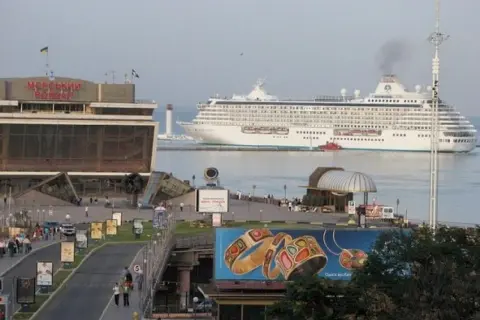 Großes Kreuzfahrtschiff verlässt den odessa port. Ein Leuchtturm wacht über die Einfahrt.