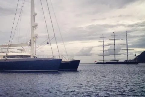 Ein großes, modernes Segelboot liegt neben einem historischen Segelschiff. Ein beeindruckender boat vs ship Vergleich.