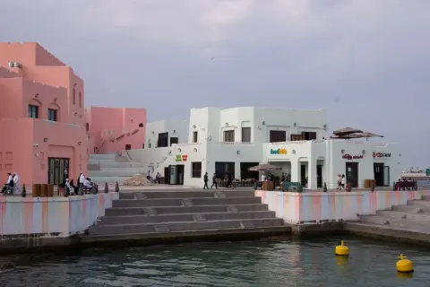 Bunte Gebäude am doha port, mit Menschen, die auf den Stufen sitzen und spazieren gehen.