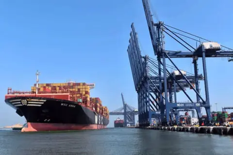 Ein riesiges Containerschiff liegt im Karachi Port vor Anker, während massive Kräne Container verladen.