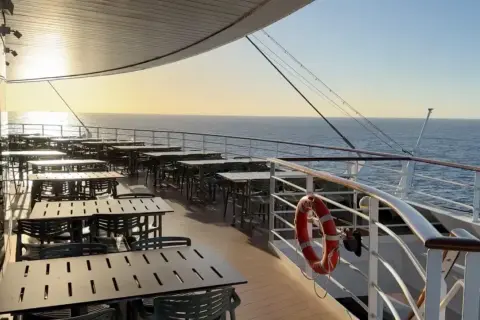 Leere Tische und Stühle auf einem Kreuzfahrtschiff-Deck bei Sonnenuntergang, bereit für die Gäste nach den marine surveys.