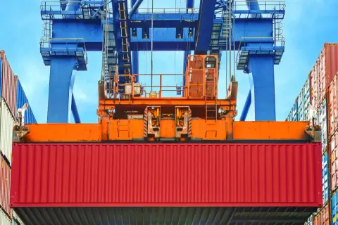 Ein roter Container wird von einem Kran gehoben. Die vgm methode 2 ist hier im Einsatz, um das Gewicht zu ermitteln.
