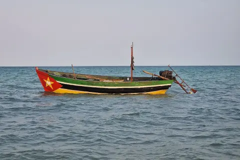 Ein bunt bemalenes Fischerboot treibt auf ruhiger See. Rot, gelb und grün zieren den Rumpf, ein Stern prangt am Bug.