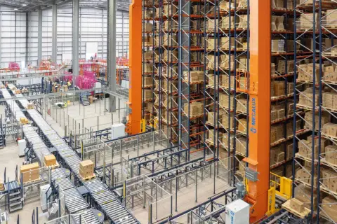 Ein Hochregallager mit automatisierten Förderbändern und einem Regalbediengerät, das für **integrated logistics** optimiert ist.
