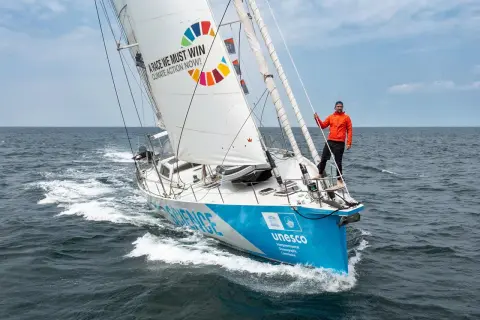 Mann auf Segelboot der Malizia Ocean Race mit Botschaft "A race we must win - Climate Action Now!".