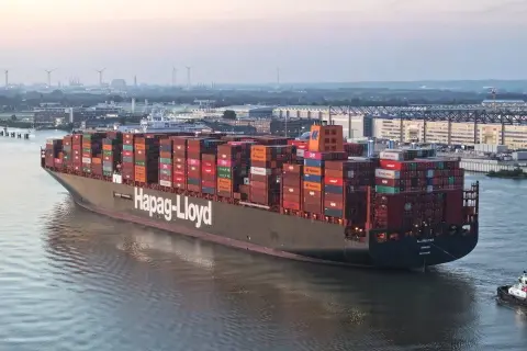 Ein riesiges Containerschiff, die "AL JMELIYAH", fährt auf einem Fluss, beladen mit bunten Frachtcontainern.