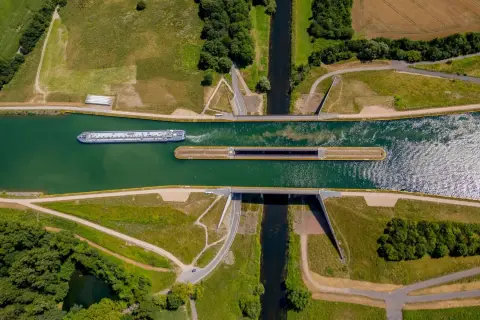 Ein großes Frachtschiff fährt auf einem Kanal. Daneben liegt eine Schleuse, bereit für das nächste Schiff.