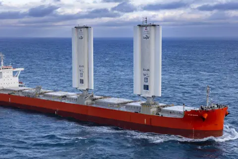 Frachtschiff mit zwei großen Windrotoren für umweltfreundliches tailwind shipping auf dem Meer.