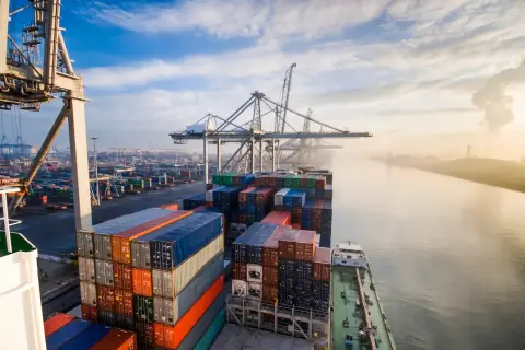 Containerriese in einem geschäftigen Hafen, ein Symbol für europäische Häfen und globalen Handel.