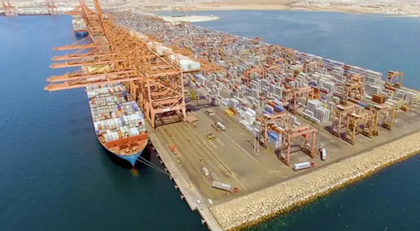 Große Containerkräne und Schiffe im Salalah Port, beladen mit unzähligen Frachtcontainern, die auf ihre Weiterreise warten.